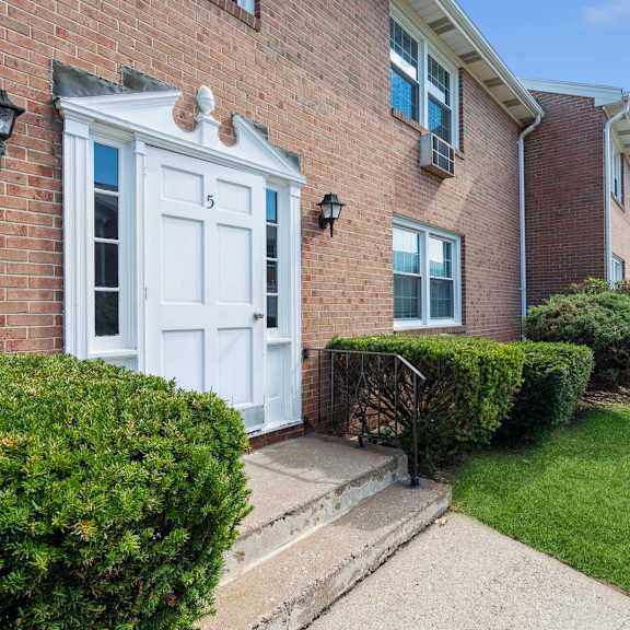 the front of a brick apartment with a white door