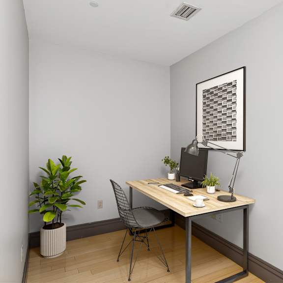 a room with a desk, chair, and a potted plant.