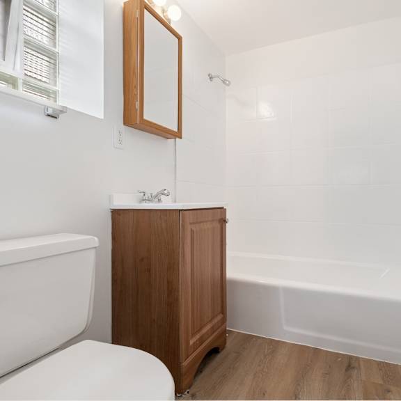 a white bathroom with a wooden cabinet and a white tub.