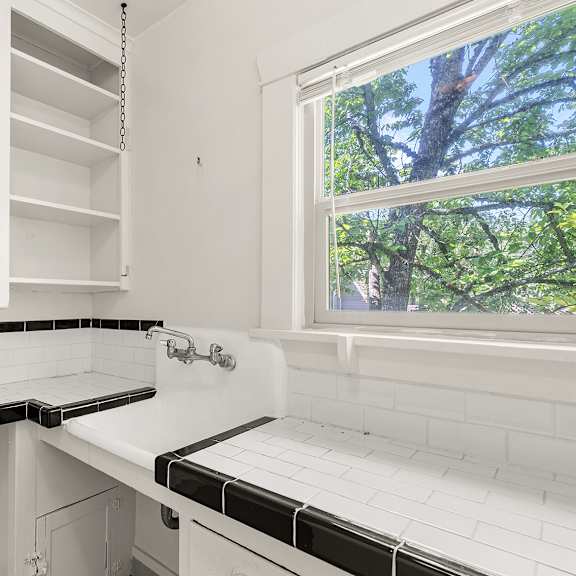 a white kitchen with black and white tiles.