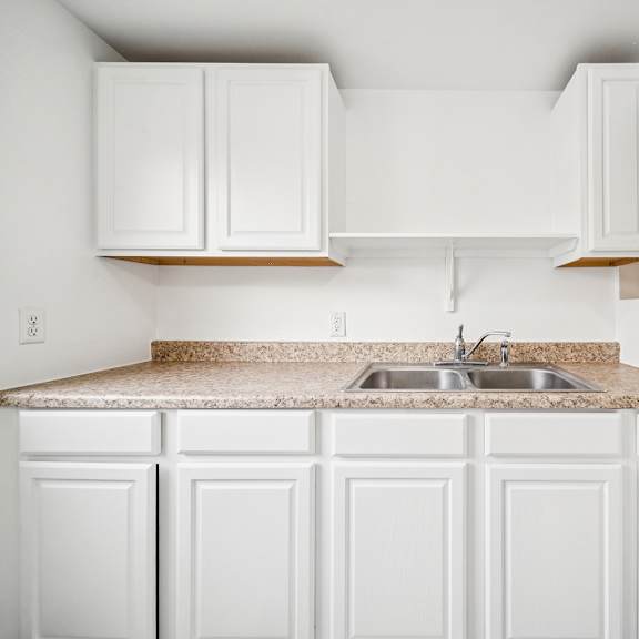 a kitchen with white cabinets and a granite countertop.