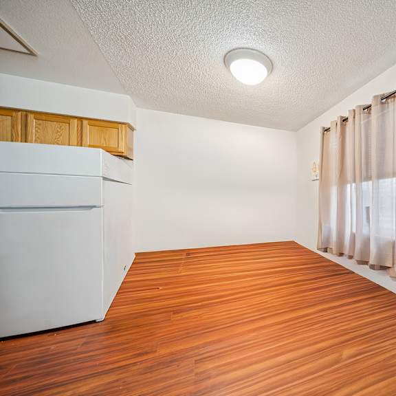 a room with wooden flooring and a white refrigerator.