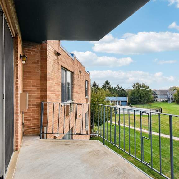 a balcony with a metal railing overlooks a green lawn.