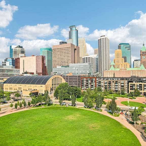 a city skyline with a green field in the foreground.