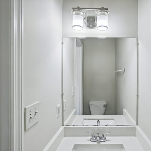 a white bathroom with a sink and mirror.