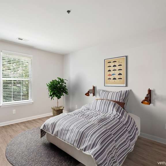 a bedroom with a bed, a plant, and a picture on the wall.