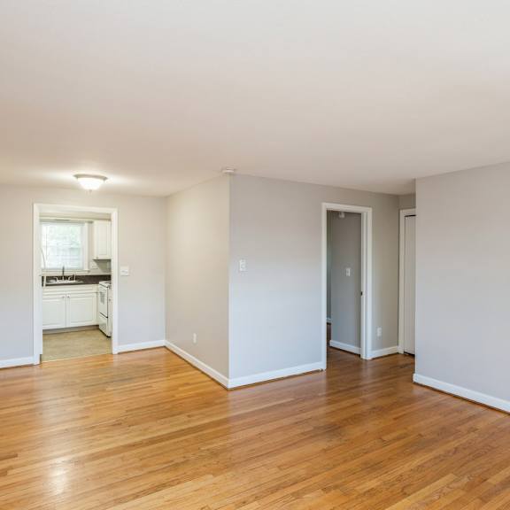 an empty living room with wood floors and white walls