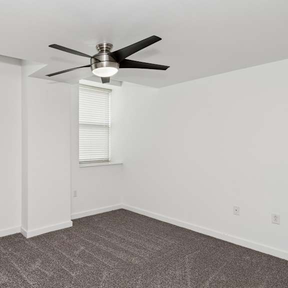 a room with a ceiling fan and carpeted floor.