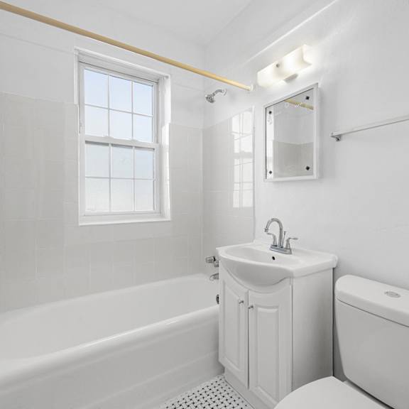a white bathroom with a tub, toilet, sink, and mirror at pleasant oak apartments, oak park, il, 60302
