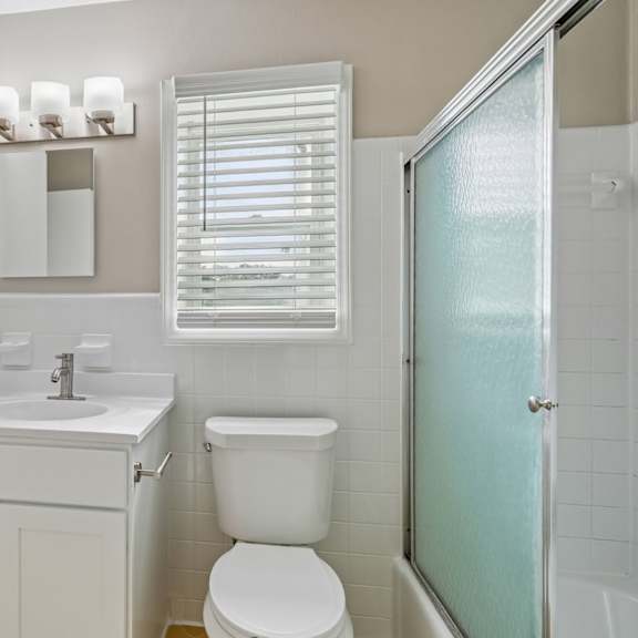 a white bathroom with a toilet, sink, and mirror.