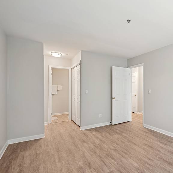 a room with white walls and wooden flooring with two doors.