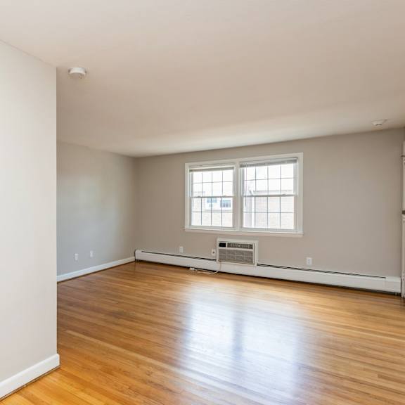 the living room of an empty house with wood floors and a window