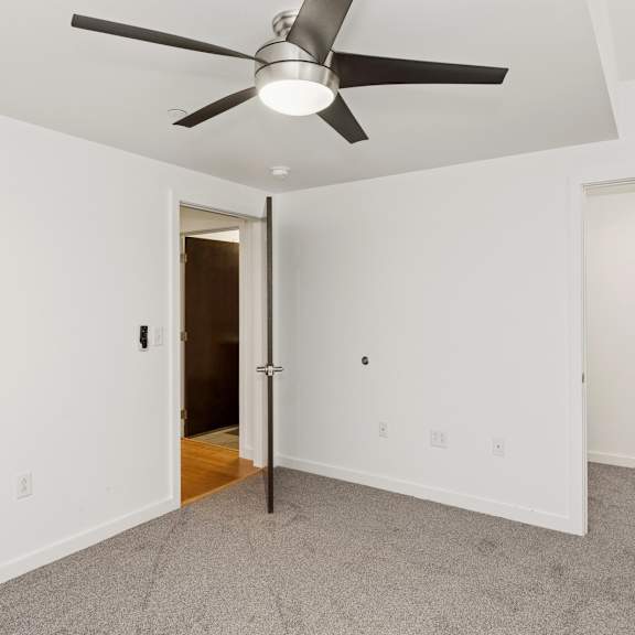 a room with a ceiling fan and a door leading to another room.