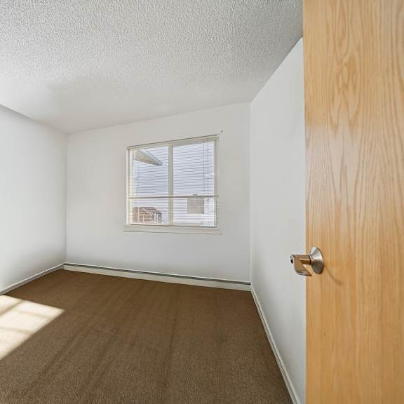 a room with a wooden door and a window with blinds.