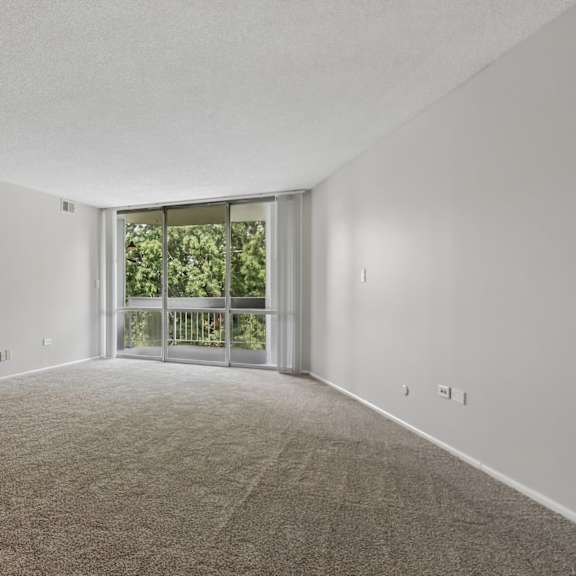 a room with a carpeted floor and a sliding glass door leading to a balcony.