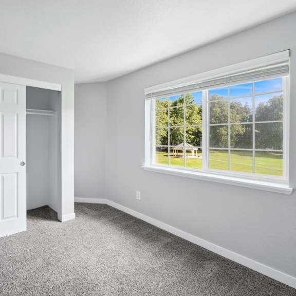a bedroom with a large window and a carpet floor at sundial apartments, wilsonvile, oregon