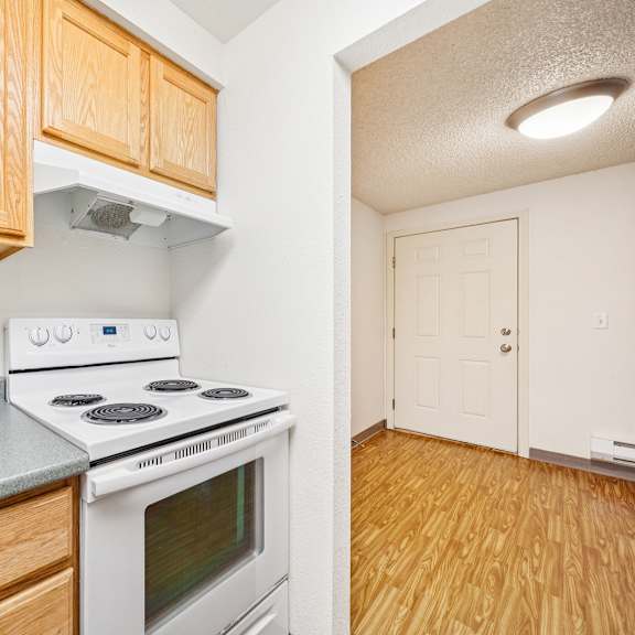 a kitchen with a white stove top oven and wooden cabinets.