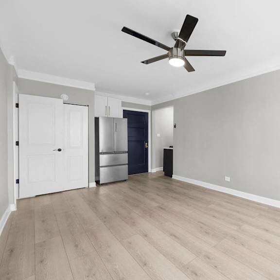 a room with a ceiling fan and light, hardwood floors, and a white door at pleasant oak apartments, illinois, 60302