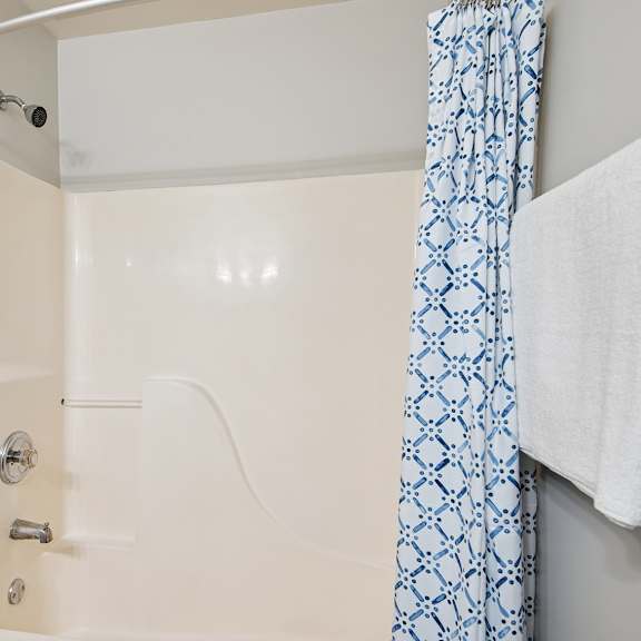 a white bathroom with a blue and white shower curtain.