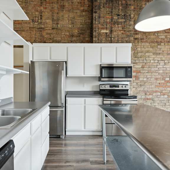 a kitchen with stainless steel countertops and a brick wallat gaar scott historic lofts, minneapolis