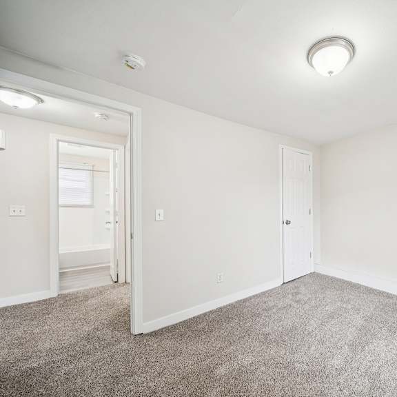 a room with a carpeted floor and a smoke detector on the ceiling.