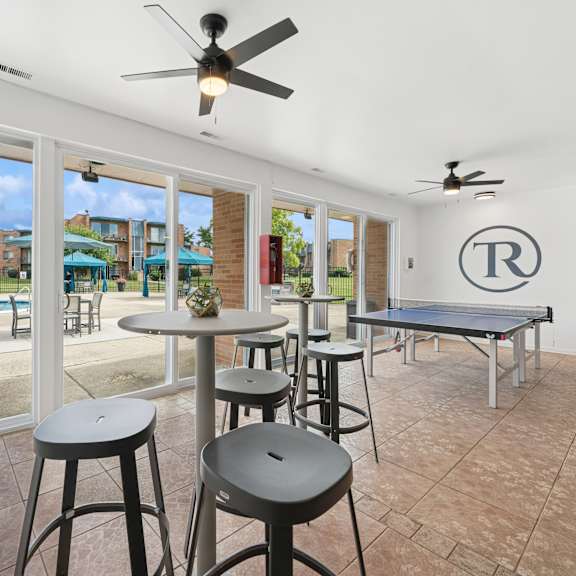 a room with a pool outside the window and a table with stools.