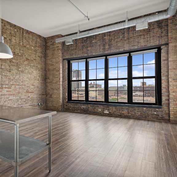 an open kitchen and dining area in an apartment with brick walls and a large windowat gaar scott historic lofts, minnesota, 55401