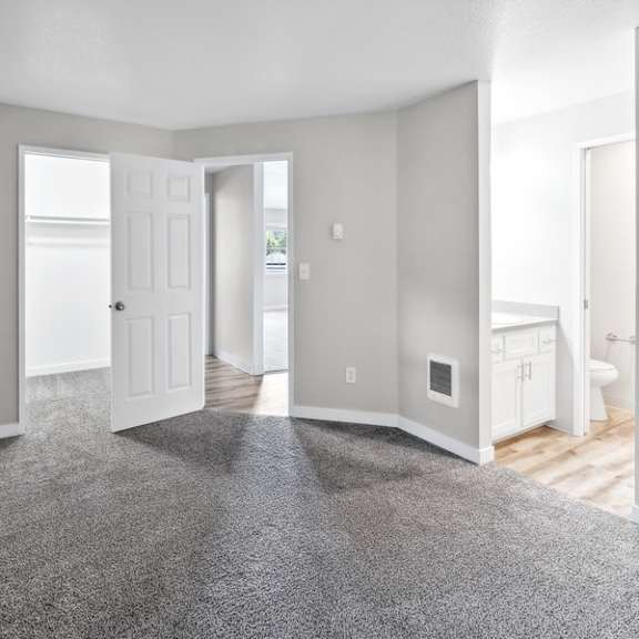 an empty  room with a carpeted floor and a door to a bathroom at sundial apartments, wilsonvile, oregon