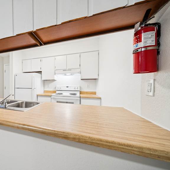 a kitchen with a wooden counter top and a red fire extinguisher on the wall.