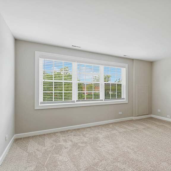 a bedroom with a large window and beige carpet at the hinsdale, illinois
