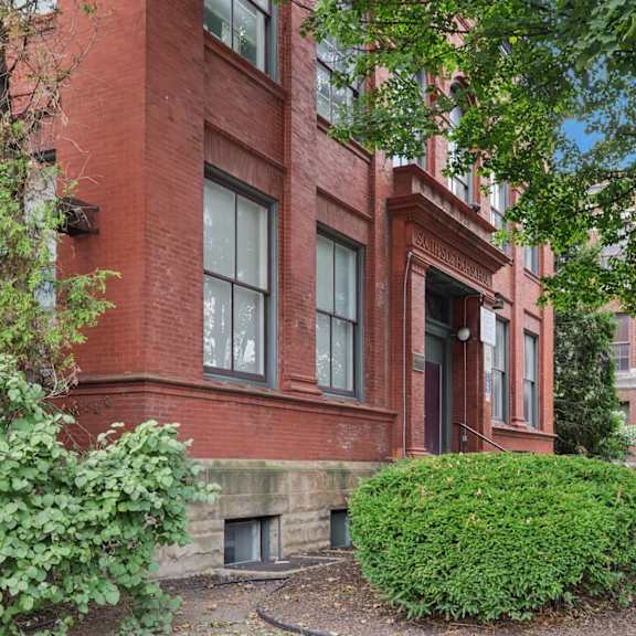 a red brick building with a green bush in front.