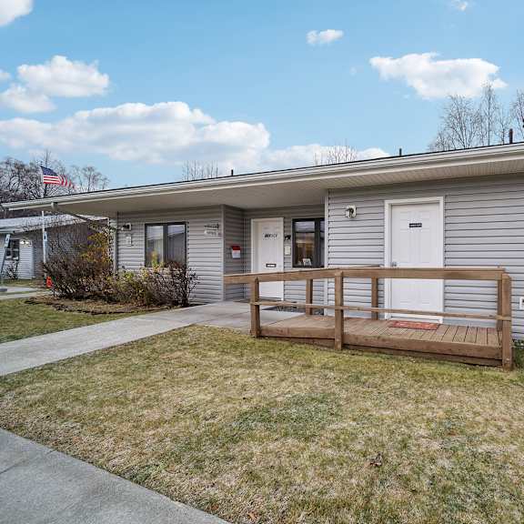 a house with a grey siding and a brown porch.