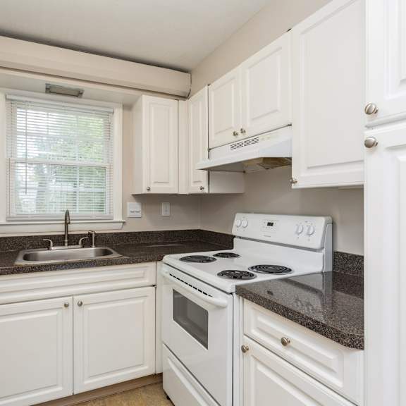 a kitchen with white appliances and granite counter tops and white cabinets