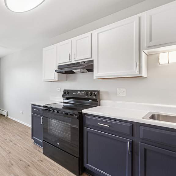 a kitchen with a black oven with white and blue cabinets.