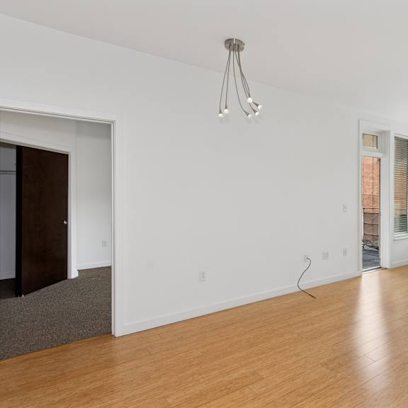 a room with wooden floors and a window with blinds.