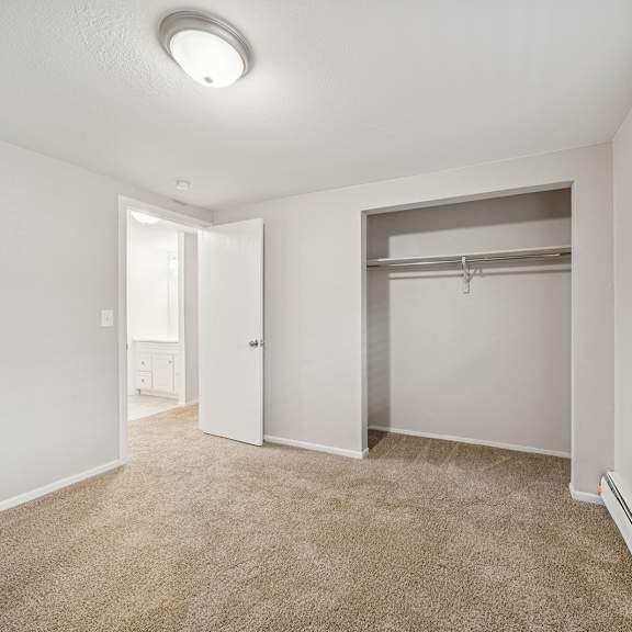 a room with a carpeted floor and a closet with a shelf.