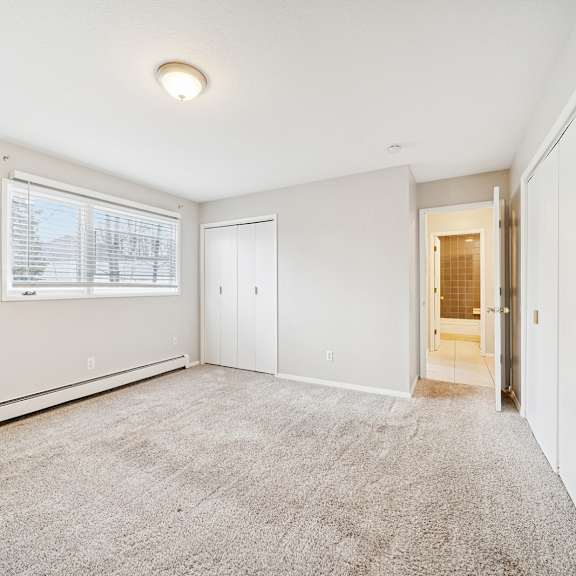a room with a carpeted floor and a window with blinds.