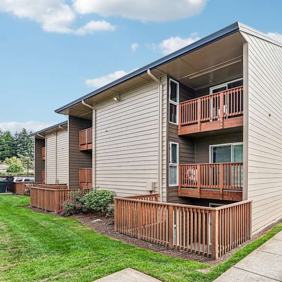 apartment building with a brown fence and green plants in front.