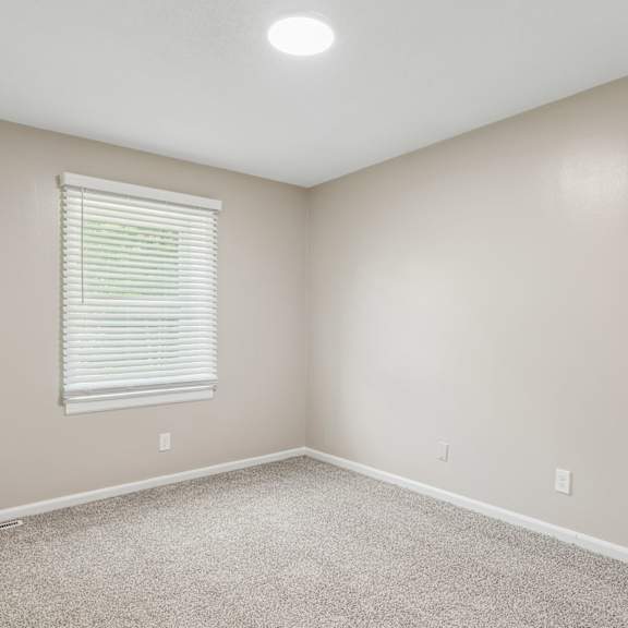 a room with a window and carpeted floor.