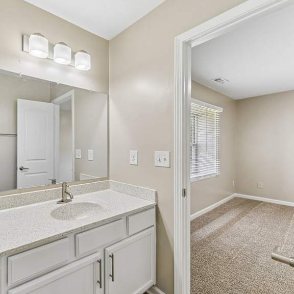 a bathroom with a white sink and a window with blinds.