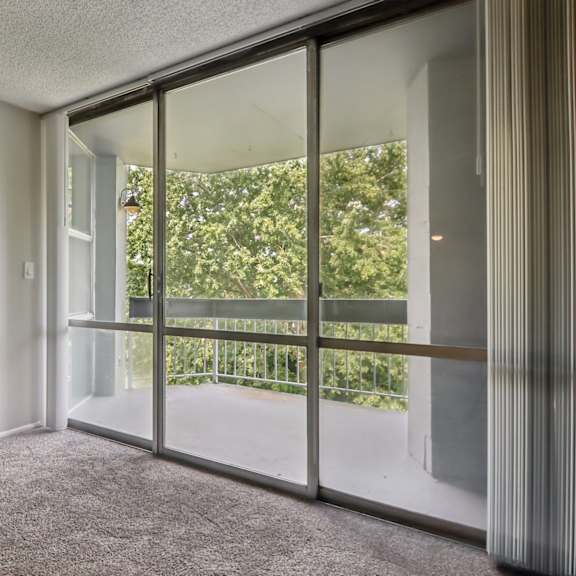 a room with a carpeted floor and a sliding glass door leading to a balcony.