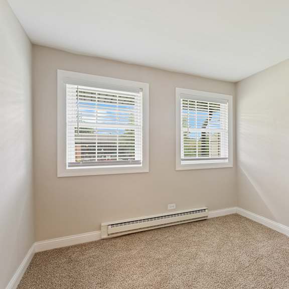 a bedroom with two windows and a carpeted floor at the hinsdale, hinsdale