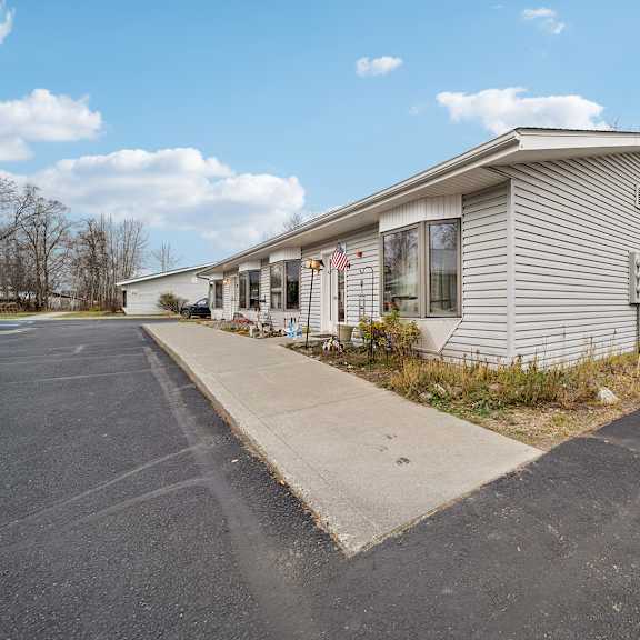 a house with a grey siding and a white roof is surrounded by a parking lot.