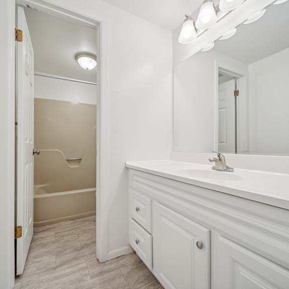 a white bathroom with a tub, sink and mirror.