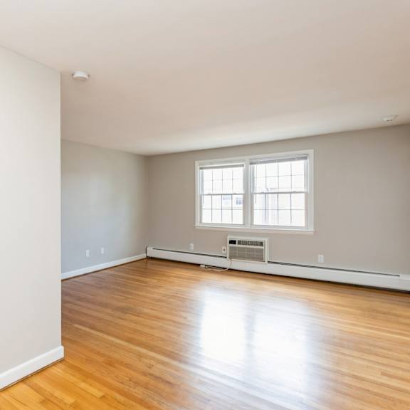 the living room of an empty house with white walls and wooden floors