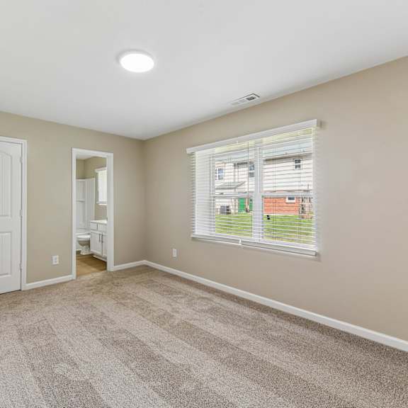 a room with a carpeted floor and a window with blinds.