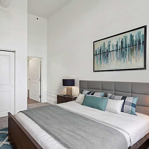 a bedroom with a bed, nightstand, and a painting on the wall.
