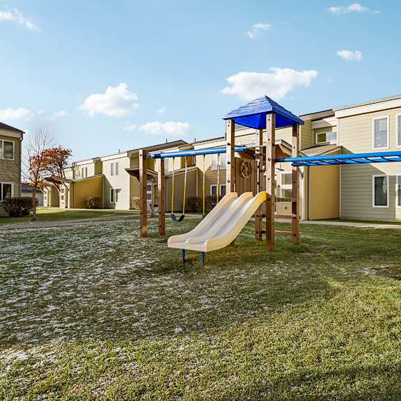 a playground with a slide and a wooden structure.