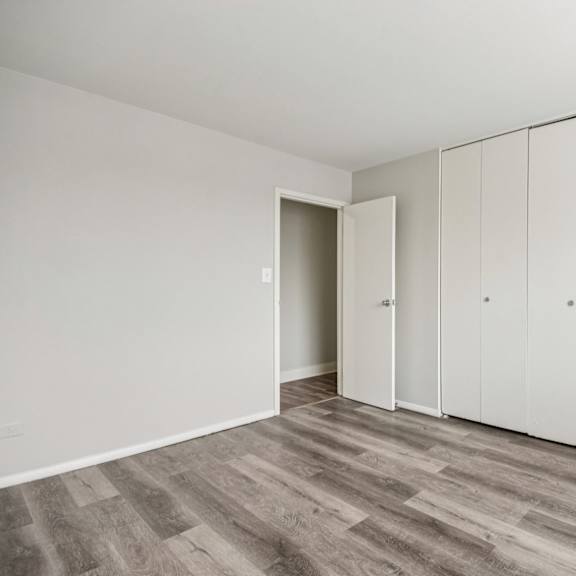 a room with a grey floor and white walls with a door and a wardrobe.