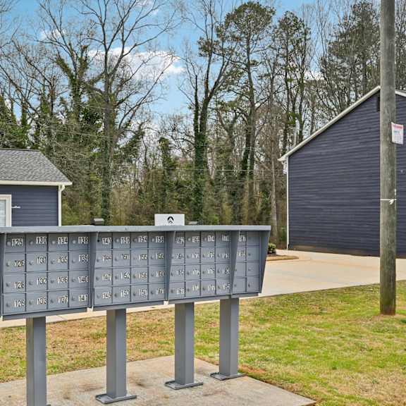 a blue mailbox with a row of mail slots in front of a house.